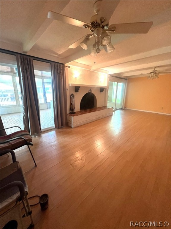 unfurnished living room with beam ceiling, ceiling fan, and light wood-type flooring