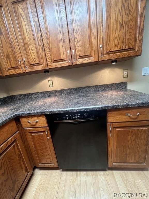 kitchen with black dishwasher, light hardwood / wood-style flooring, and dark stone countertops