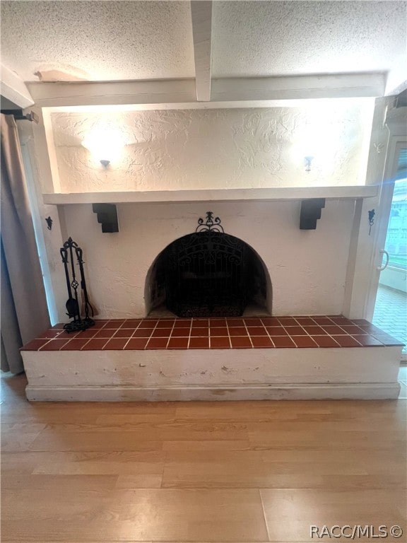 details featuring beamed ceiling, a textured ceiling, hardwood / wood-style flooring, and a fireplace