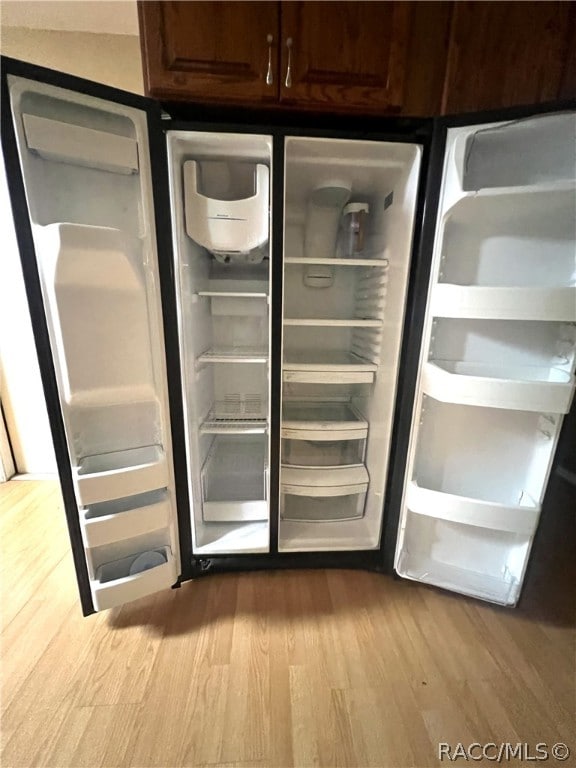 details with dark brown cabinets, light hardwood / wood-style flooring, and stainless steel refrigerator