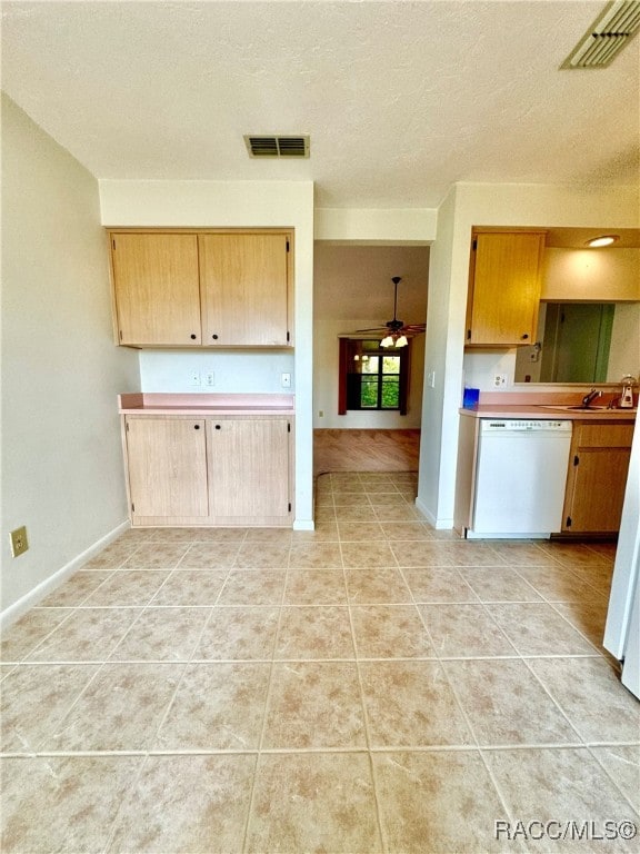 kitchen with white dishwasher, sink, ceiling fan, a textured ceiling, and light tile patterned flooring