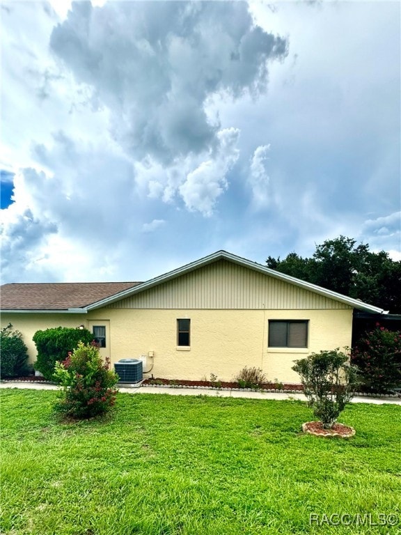 view of side of property with a yard and central AC