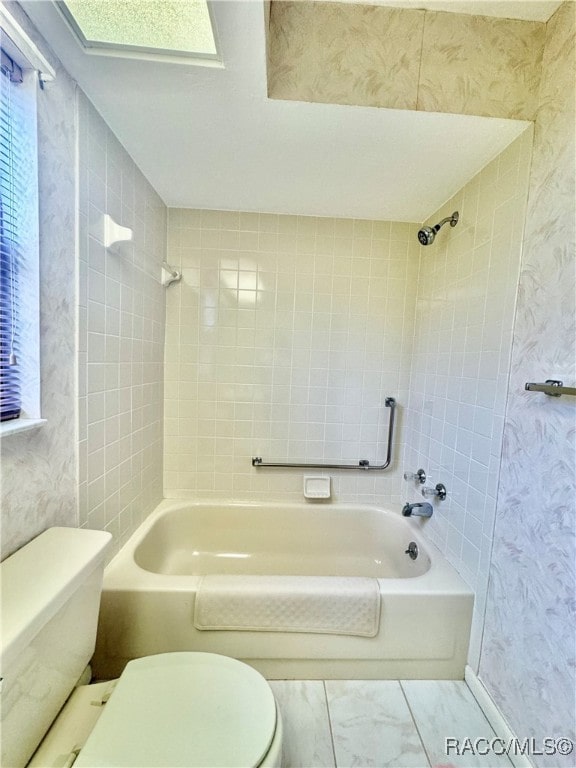 bathroom featuring tiled shower / bath combo and toilet