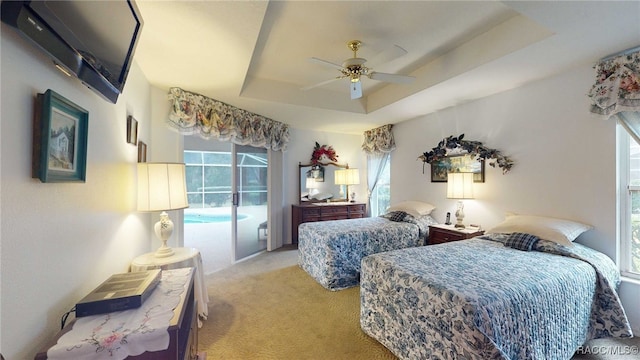 carpeted bedroom with access to outside, a raised ceiling, and ceiling fan