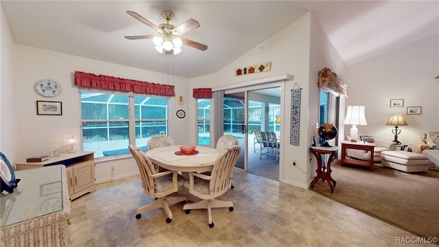 carpeted dining area with ceiling fan, a healthy amount of sunlight, and vaulted ceiling