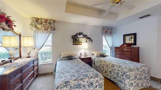 bedroom with ceiling fan, light carpet, and a raised ceiling