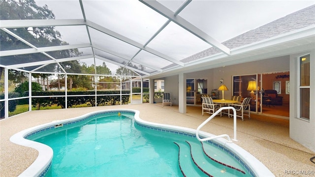 view of pool with glass enclosure and a patio