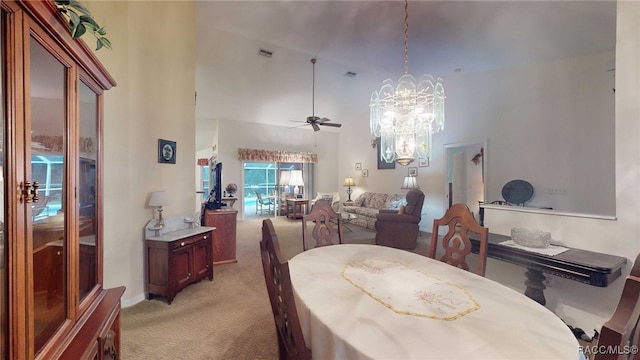 carpeted dining space featuring ceiling fan with notable chandelier and high vaulted ceiling