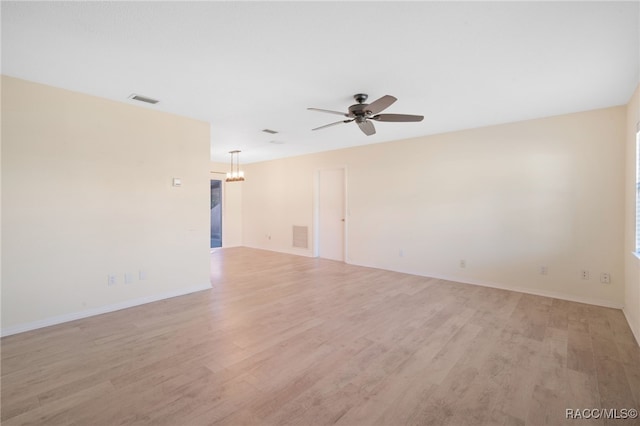 empty room featuring ceiling fan with notable chandelier and light hardwood / wood-style floors