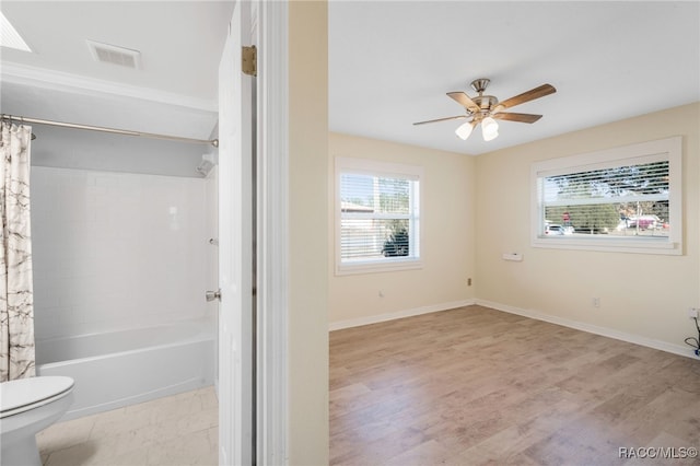 bathroom featuring hardwood / wood-style flooring, shower / bath combo, ceiling fan, and toilet