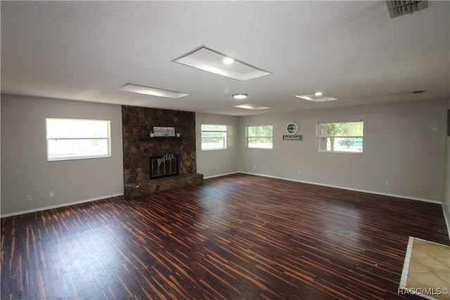 unfurnished living room with a fireplace, dark wood finished floors, visible vents, and baseboards