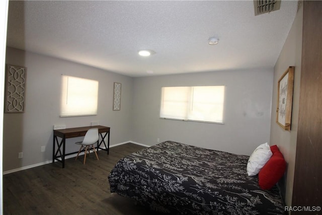 bedroom featuring baseboards, a textured ceiling, visible vents, and dark wood-type flooring