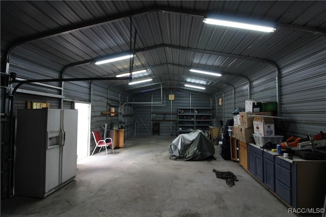 garage featuring white refrigerator with ice dispenser and metal wall