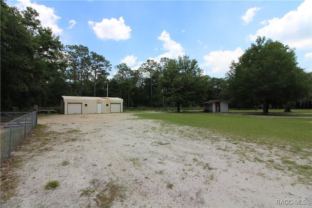 view of yard featuring a garage, an outdoor structure, and fence