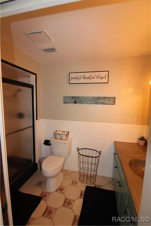 full bath with tile walls, visible vents, vanity, and a shower stall