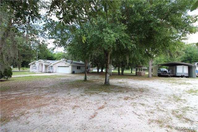 view of yard featuring a carport, driveway, and an attached garage