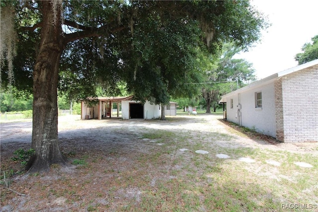 view of yard with dirt driveway, a detached garage, an outdoor structure, and an outbuilding