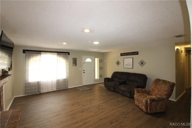 living area featuring dark wood-style floors, a textured ceiling, and baseboards