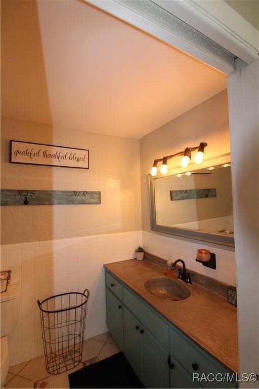 bathroom with tile walls, tile patterned flooring, wainscoting, and vanity