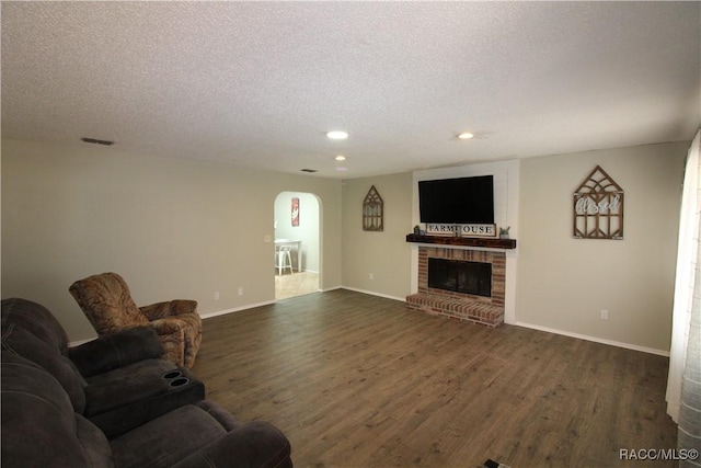 living area with dark wood-style floors, visible vents, a fireplace, and a textured ceiling