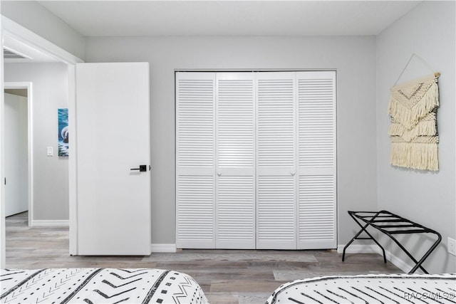 bedroom with a closet, baseboards, visible vents, and wood finished floors