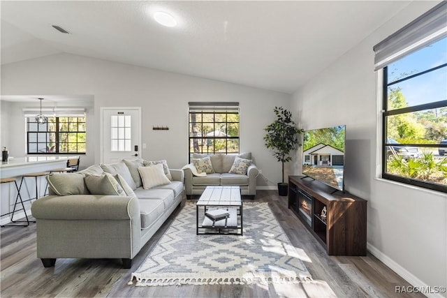 living room featuring plenty of natural light, wood finished floors, and vaulted ceiling