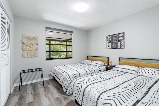 bedroom with wood finished floors, baseboards, and a closet