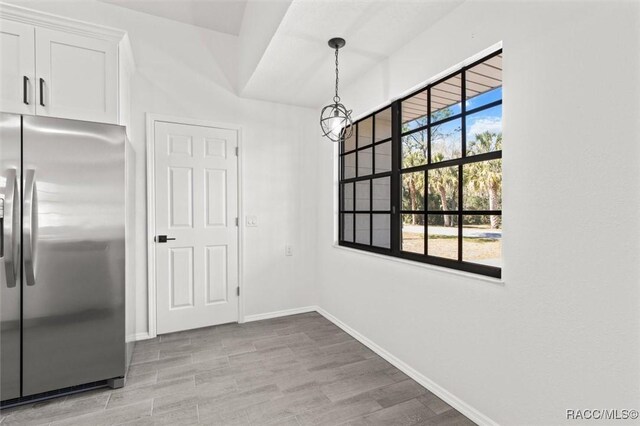 unfurnished dining area with baseboards and light wood-style floors