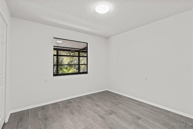 unfurnished room with wood finished floors, baseboards, and a textured ceiling