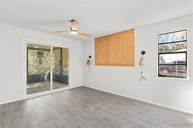 empty room featuring plenty of natural light, wood finished floors, baseboards, and ceiling fan