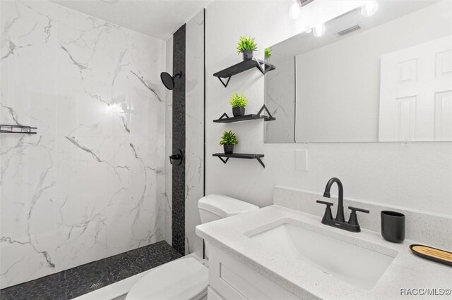 full bathroom featuring a marble finish shower, visible vents, toilet, and vanity