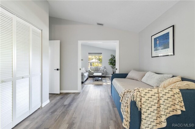 living room featuring visible vents, baseboards, wood finished floors, and vaulted ceiling