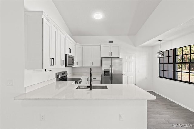 kitchen featuring light countertops, appliances with stainless steel finishes, a peninsula, white cabinetry, and a sink