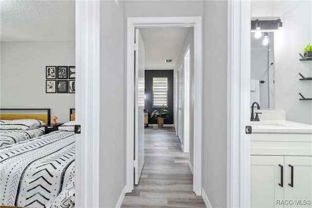 corridor with a sink, baseboards, and light wood finished floors