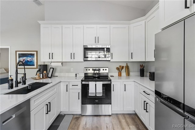 kitchen featuring visible vents, a sink, stainless steel appliances, white cabinets, and light countertops