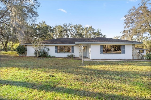 single story home with stucco siding and a front yard