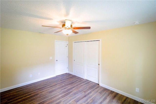 unfurnished bedroom with ceiling fan, a closet, and dark wood-type flooring