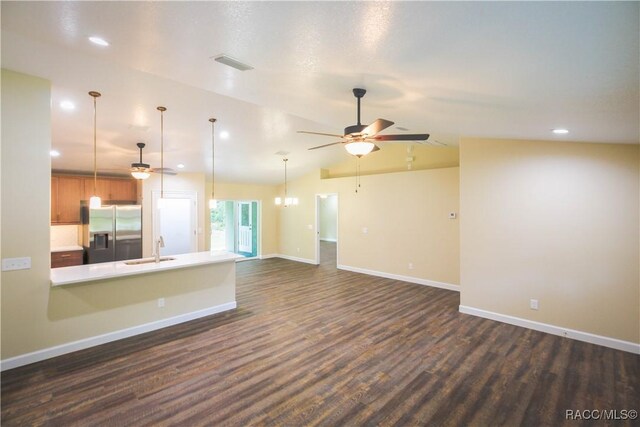 unfurnished living room with dark hardwood / wood-style floors, sink, lofted ceiling, and ceiling fan with notable chandelier