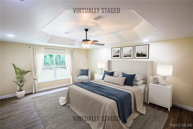 bedroom featuring a tray ceiling, ceiling fan, and dark wood-type flooring