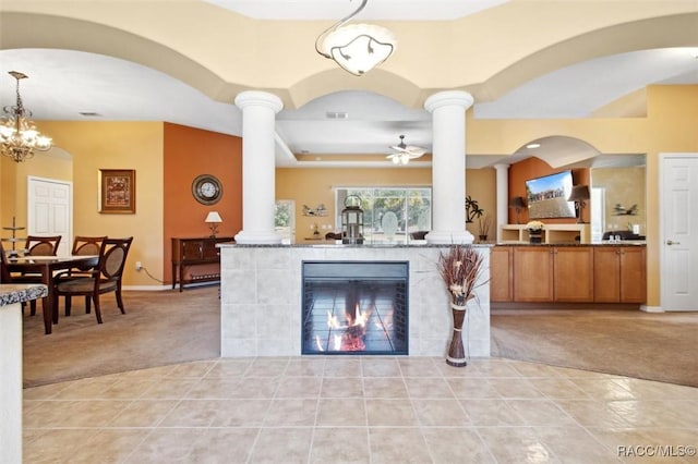 interior space featuring light colored carpet, decorative light fixtures, ceiling fan with notable chandelier, and a fireplace