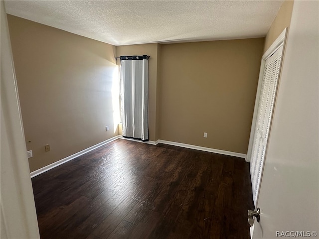 unfurnished bedroom with dark wood-type flooring and a textured ceiling