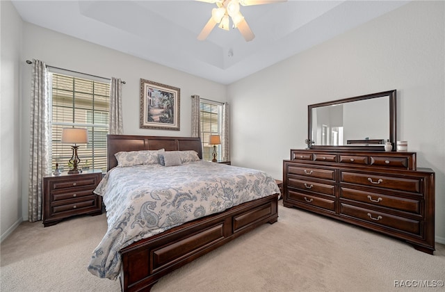 bedroom with ceiling fan, a raised ceiling, and light carpet