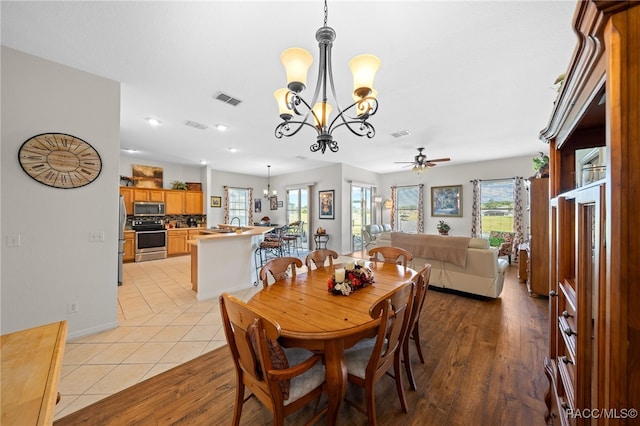 dining room with ceiling fan with notable chandelier and light hardwood / wood-style floors