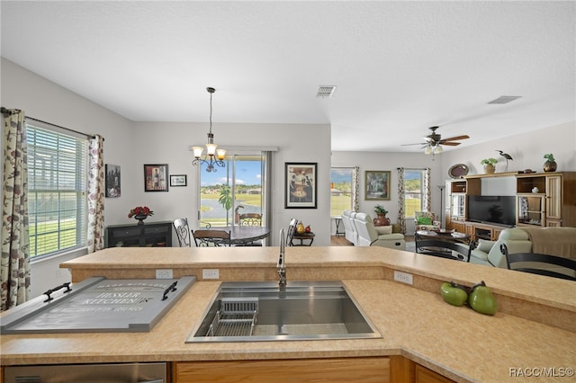 kitchen with ceiling fan with notable chandelier, hanging light fixtures, a healthy amount of sunlight, and sink