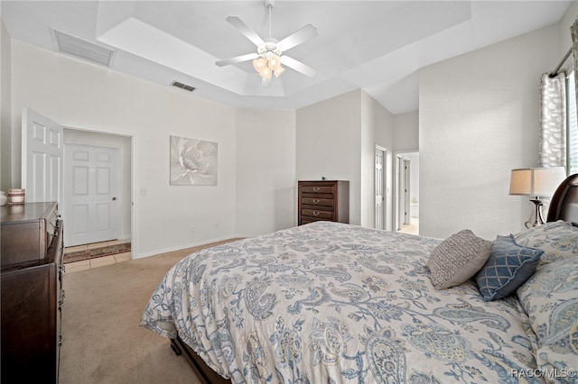 carpeted bedroom featuring a raised ceiling and ceiling fan