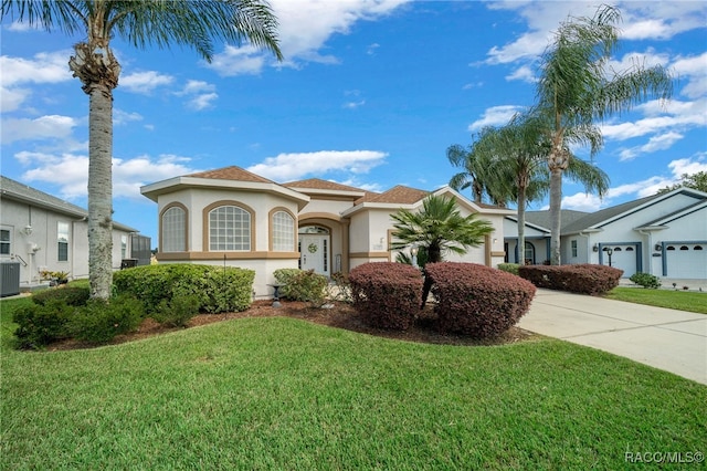 mediterranean / spanish house featuring a front lawn, a garage, and cooling unit