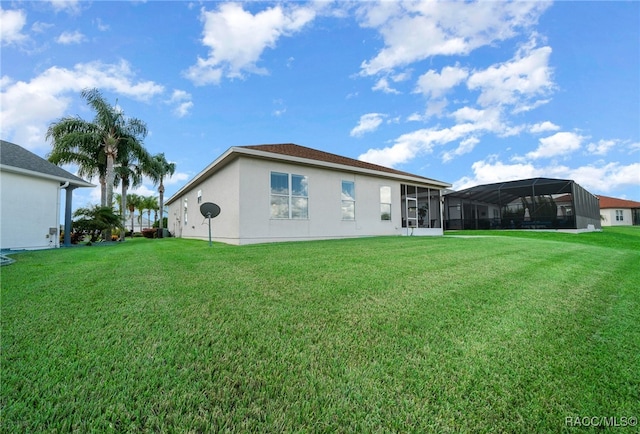 back of house with glass enclosure and a yard