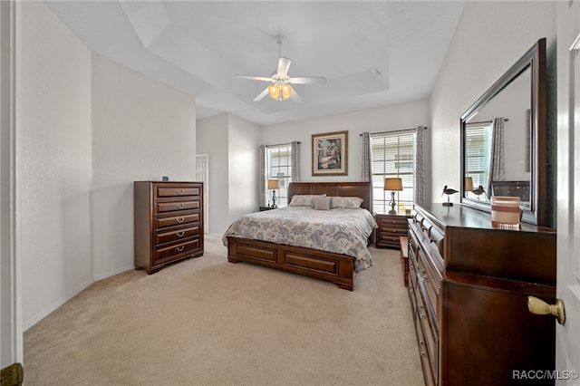 bedroom featuring light colored carpet, ceiling fan, and a tray ceiling