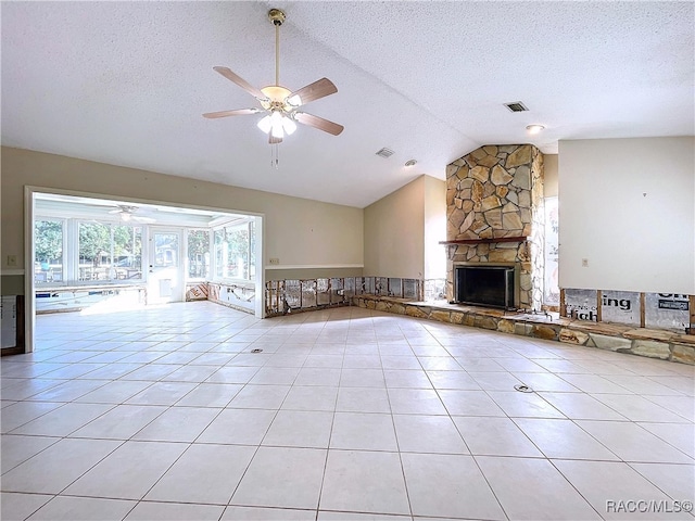 unfurnished living room with light tile patterned flooring, a stone fireplace, lofted ceiling, ceiling fan, and a textured ceiling