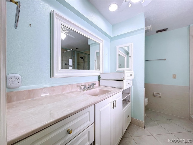 bathroom featuring walk in shower, toilet, tile walls, vanity, and tile patterned flooring